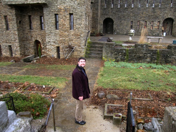 Man stands in the small courtyard near a castle.